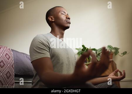 Junger afrikanischer Mann, der zu Hause in seinem Schlafzimmer meditiert Stockfoto