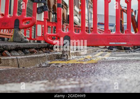 Kidderminster, Großbritannien. Oktober 2021. Eine geplatzte Wasserleitung hat heute Morgen in Kidderminster zu erheblichen Verkehrsstörungen geführt. Der Combertion Hill Highway, der zum Bahnhof Kidderminster führt, wurde aufgrund von Reinigungsarbeiten und Reparaturen gesperrt. Ein Zuschauer, der gestern Abend die geplatzte Wasserleitung sah, sagte, die Straße sah aus, als ob sie schwebte und begann dann einzustürzen, während der Verkehr zu der Zeit weiter über sie fuhr. Die gesamte Oberfläche der Straße hat sich angehoben, ebenso der Fußweg, durch den noch immer Wasser tropft. Kredit: Lee Hudson/Alamy Live Nachrichten Stockfoto