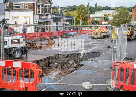 Kidderminster, Großbritannien. Oktober 2021. Eine geplatzte Wasserleitung hat heute Morgen in Kidderminster zu erheblichen Verkehrsstörungen geführt. Der Combertion Hill Highway, der zum Bahnhof Kidderminster führt, wurde aufgrund von Reinigungsarbeiten und Reparaturen gesperrt. Ein Zuschauer, der gestern Abend die geplatzte Wasserleitung sah, sagte, die Straße sah aus, als ob sie schwebte und begann dann einzustürzen, während der Verkehr zu der Zeit weiter über sie fuhr. Die gesamte Oberfläche der Straße hat sich angehoben, ebenso der Fußweg, durch den noch immer Wasser tropft. Kredit: Lee Hudson/Alamy Live Nachrichten Stockfoto