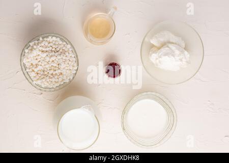 Draufsicht auf verschiedene Zutaten für die Zubereitung von weißer heißer Schokolade auf weißem Hintergrund im Studio angeordnet Stockfoto