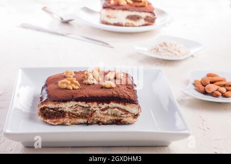 Hoher Winkel von köstlichen Tiramisu Dessert garniert mit Walnüssen serviert auf weißem Tisch Stockfoto