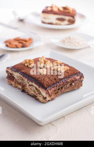 Hoher Winkel von köstlichen Tiramisu Dessert garniert mit Walnüssen serviert auf weißem Tisch Stockfoto