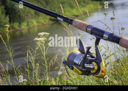 Am Ufer des schönen Flusses über dem Wasserzubringer installiert - Englisch Angelgerät für den Fang von Fischen bequem mit der Rute und der Haspel. Stockfoto