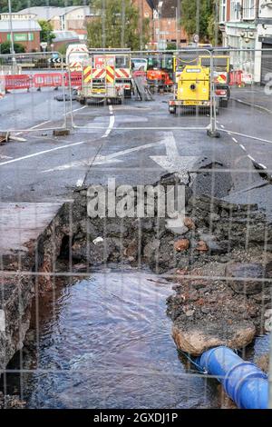 Kidderminster, Großbritannien. Oktober 2021. Eine geplatzte Wasserleitung hat heute Morgen in Kidderminster zu erheblichen Verkehrsstörungen geführt. Der Combertion Hill Highway, der zum Bahnhof Kidderminster führt, wurde aufgrund von Reinigungsarbeiten und Reparaturen gesperrt. Ein Zuschauer, der gestern Abend die geplatzte Wasserleitung sah, sagte, die Straße sah aus, als ob sie schwebte und begann dann einzustürzen, während der Verkehr zu der Zeit weiter über sie fuhr. Die gesamte Oberfläche der Straße hat sich angehoben, ebenso der Fußweg, durch den noch immer Wasser tropft. Kredit: Lee Hudson/Alamy Live Nachrichten Stockfoto