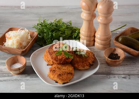Saftig gebratene hausgemachte Hähnchenschnitzel. Mit Paniermehl überzogen, köstlich, in weißer Schale mit Kräutern. Auf altem Holzhintergrund, rustikaler Stil Stockfoto