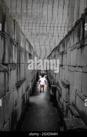 Kaukasisches junges Kind, das mit Labyrinthperspektive läuft. Konzeptuelles Bild für gefährliche Situationen in der Kindheit. Stockfoto