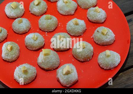 Hausgemachte Milch Süßigkeiten genannt beijinho serviert auf einem roten Tablett Süßigkeiten für Geburtstagsfeier. Köstliche Desserts. Dekorierte Küsse und serviert auf einem bunten Pl Stockfoto