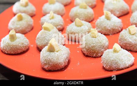 Hausgemachte Milch Süßigkeiten genannt beijinho serviert auf einem roten Tablett Süßigkeiten für Geburtstagsfeier. Köstliche Desserts. Dekorierte Küsse und serviert auf einem bunten Pl Stockfoto