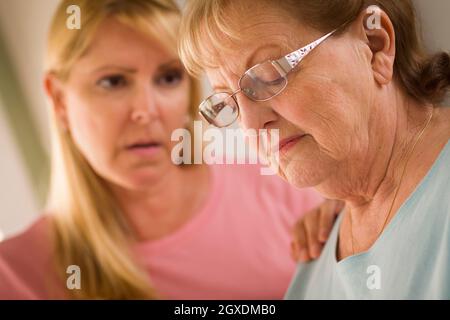 Junge Frau tröstet traurige Senior Erwachsenfrau. Stockfoto