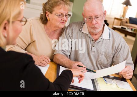 Senior paar Papiere in ihrer Heimat mit Agent durchgehen. Stockfoto