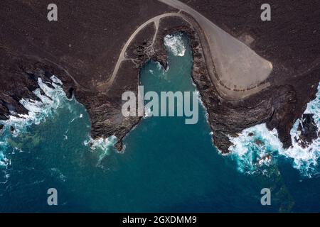 Drohnenansicht des schäumenden Meeres gegen geschwungene Straßen und Berge mit Hervideros in Yaiza Lanzarote Kanarische Inseln Spanien Stockfoto