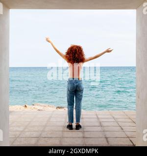 Von unten Seitenansicht des bärtigen männlichen Hipsters mit künstlichem Arm, der im Sommer in der Stadt Fahrrad entlang der Straße reitet Stockfoto