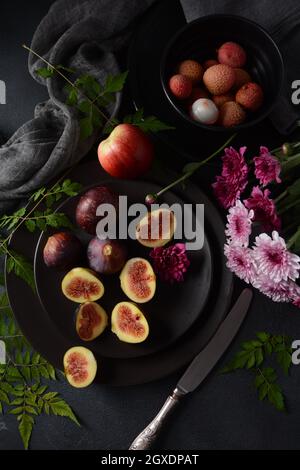 Rohe frische Feigenfrüchte auf dunklem Hintergrund. Scheiben frischer gewöhnlicher Feige (Ficus carica) Stockfoto