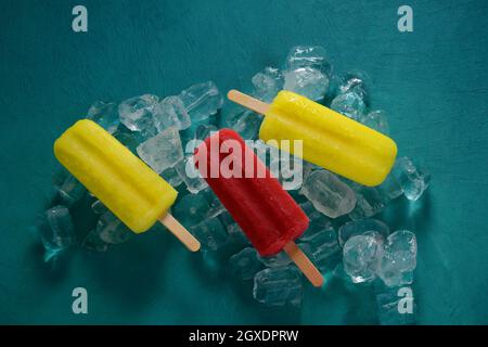 Erdbeerpopsicle und Zitronenpopsicle auf blauem Hintergrund mit Eis Stockfoto