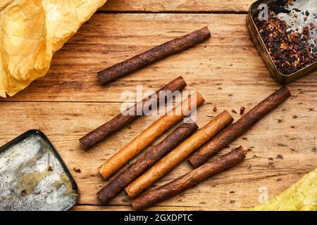 Zigarillos und trockenes Tabakblatt auf Holzhintergrund Stockfoto