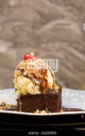 Vanilleeis mit Schokoladensauce und zerkleinerten Nüssen Serviert mit Brownie-Kuchen Stockfoto