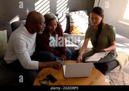 afroamerikanisches Seniorenpaar, das sich zu Hause mit einer asiatischen Finanzberaterin getroffen hat Stockfoto