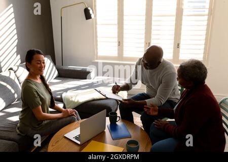 afroamerikanisches Seniorenpaar, das sich zu Hause mit einer asiatischen Finanzberaterin getroffen hat Stockfoto