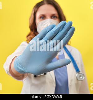 Der Arzt zeigt mit seinen Händen eine Verbotsgeste, Nahaufnahme. Hand in medizinischen Handschuhen mit einer Geste des Stopps, Konzept der Resistenz des Epids Stockfoto