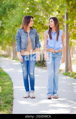 Junge Erwachsene Mixed Race Twin Sisters, Die Draußen Gemeinsam Spazieren. Stockfoto