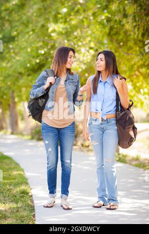 Junge Erwachsene Mixed Race Twin Sisters, Die Draußen In Rucksäcken Zusammenlaufen. Stockfoto