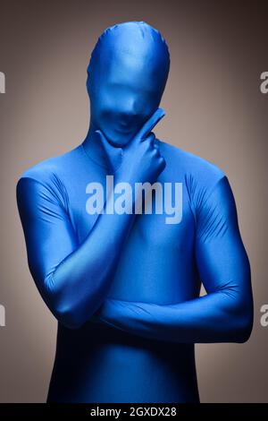 Denkenden Menschen mit Hand am Kinn tragen volle blau Nylon Body auf einem grauen Hintergrund. Stockfoto