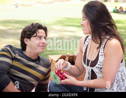 Attraktives hispanische paar mit einem Picknick im Freien im Park. Stockfoto