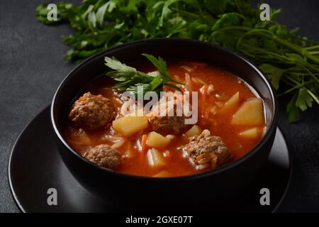 Patatesli Sulu Kofte - Turkish soup with meatballs in black bowl Stock Photo