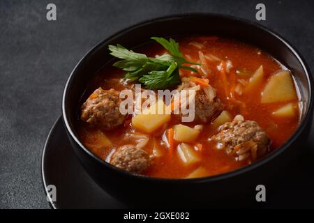 Patatesli Sulu Kofte - Turkish soup with meatballs in black bowl Stock Photo