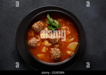 Patatesli Sulu Kofte - Turkish soup with meatballs in black bowl Stock Photo