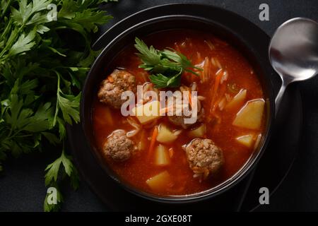 Patatesli Sulu Kofte - Turkish soup with meatballs in black bowl Stock Photo