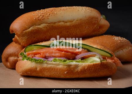 Baguette Sub Sandwich mit Lachsfisch, Zwiebeln, Gurken, Salat Stockfoto