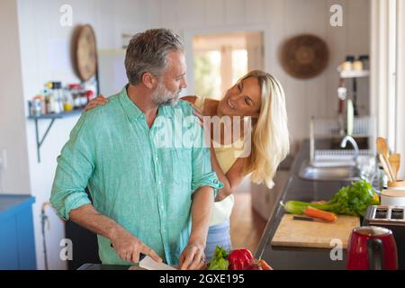 Glückliches kaukasisches reifes Paar kocht zusammen in der modernen Küche Stockfoto