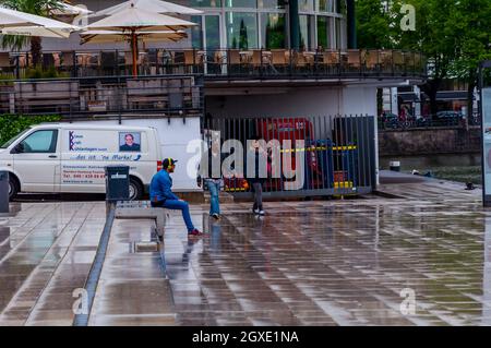 Hamburg, Deutschland, Mai 08. 2014, Schwarze auf dem Bürgersteig in Hamburg und Kaukasischer Mann mit Kopfhörern sitzen und durch den See schauen Stockfoto