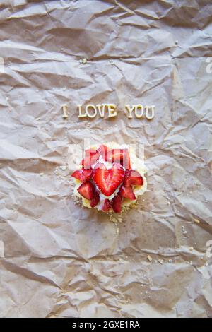 Helle Cupcake mit Erdbeeren liegt auf Handwerk Papier, die Inschrift ich liebe Dich. Stockfoto