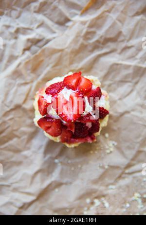 Schöne Muffin mit frischen Erdbeeren liegt auf Handwerk Papier, close-up. Stockfoto