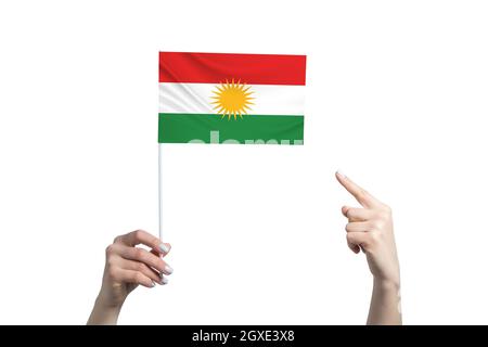 Eine schöne weibliche Hand hält eine Flagge Kurdistans, auf der sie den Finger ihrer anderen Hand zeigt, isoliert auf weißem Hintergrund. Stockfoto