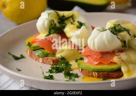 Eier Benedikt mit geräuchertem Lachs, Avocado-Scheiben und Sauce Hollandaise Stockfoto