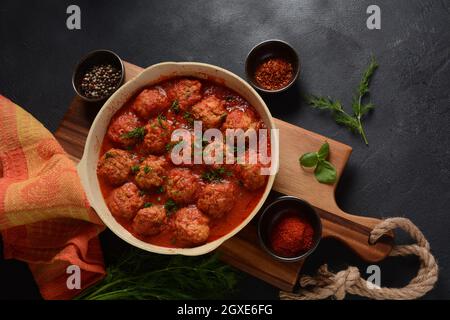 Boulettes de Poisson, gebratene Fischbälle in Tomatensauce in einer weißen Schale auf einem Betontisch mit Zutaten Stockfoto