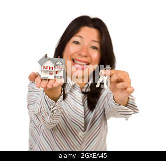 Attraktive multiethnischen Frau Holding Häuschen und Schlüssel isoliert auf einem weißen Hintergrund - konzentriert sich auf das Haus und die Schlüssel. Stockfoto