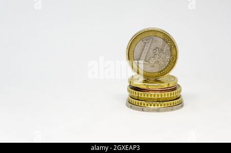 Verschiedene Euro-Münzen gestapelt, auf denen eine Euro-Münze steht. Münzen isoliert auf weißem Hintergrund. Wirtschaft und Finanzen. Währung der Europäischen Union. Stockfoto