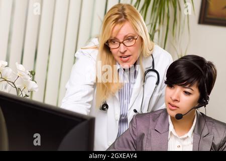 Weiblichen Arzt bespricht Arbeit am Computer mit Empfangsdame Assistentin in einer Büroumgebung. Stockfoto