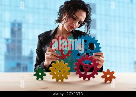 Geschäftsfrau versucht Gänge Stücke zu verbinden. Konzept der Teamarbeit, Partnerschaft und Business Integration Stockfoto