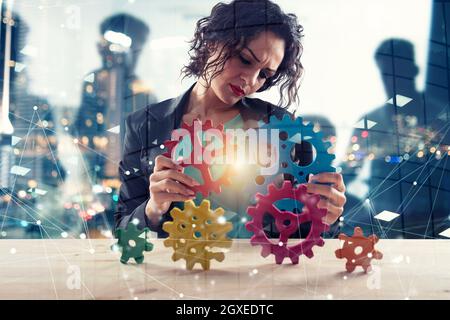 Geschäftsfrau versucht Gänge Stücke zu verbinden. Konzept der Teamarbeit, Partnerschaft und Business Integration. Double Exposure Stockfoto