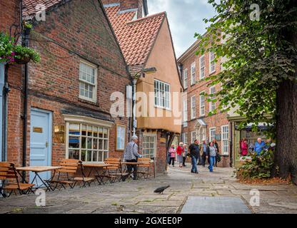 Ein malerisches mittelalterliches Gebäude mit seinen alten Holzsparren, die in einer historischen Stadt aufgestellt sind. Ein Baum ist auf der einen Seite und eine Taube ist auf den Pflastersteinen. Stockfoto