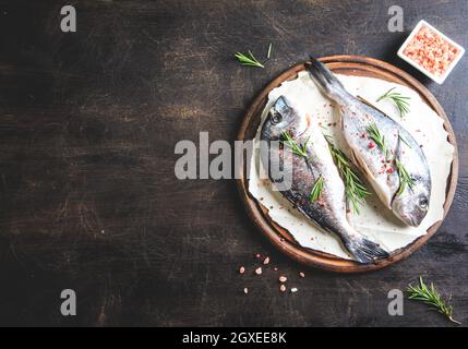 Frischer, roher dorado-Fisch auf einem Holzbrett mit rosafarbenem himalaya-Salz, rosa Pfefferkörnern und Rosmarin Stockfoto