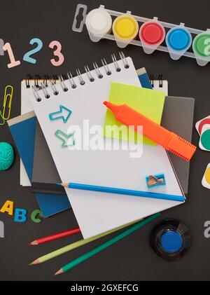 Über dem Kopf gedrehte Schreibwaren auf einem Holzschreibtisch mit Notizblock aus Papier und Rahmen mit Büromaterial für die Schule Stockfoto