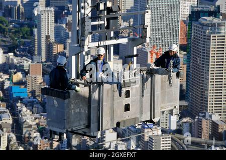 Drei Bauarbeiter auf einem Kran oben auf dem Mori Tower, Roppongi Hills, Tokio, Japan Stockfoto