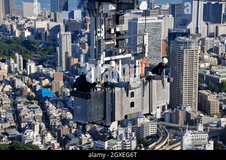 Drei Bauarbeiter auf einem Kran oben auf dem Mori Tower, Roppongi Hills, Tokio, Japan Stockfoto