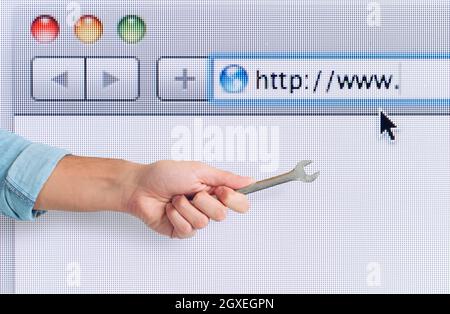 Hand mit Schraubenschlüssel über einen Internet-Webbrowser Stockfoto